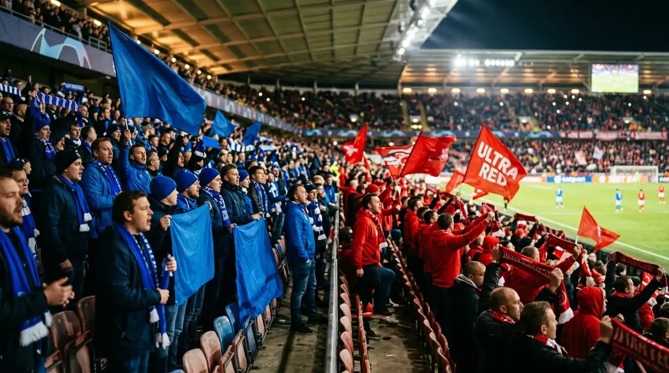 Tifosi con sciarpe e bandiere di due colori diversi affiancati sugli spalti di uno stadio coperto durante una partita di calcio serale